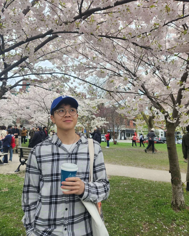 Michael under cherry blossoms in a Toronto park, coffee in hand.