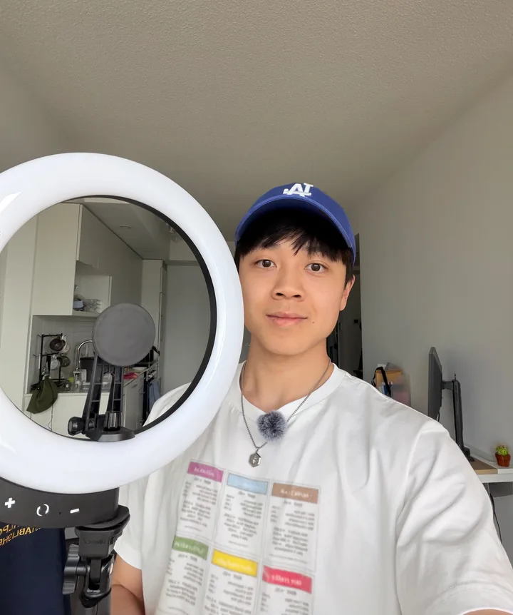 Michael in a cap beside a ring light, filming at home.